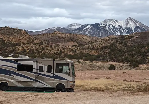 Class a motorhome parked at altitude with snowy mountains in the background. 