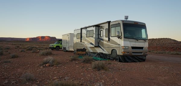 picture of class a motorhome camper wth generator that is skirted. Red mesas are in the background. 