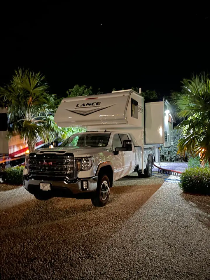 Beautiful sites at Grassy Key RV park in Florida with a truck and truck top camper pictured in the evening. Palm trees surround the campsite