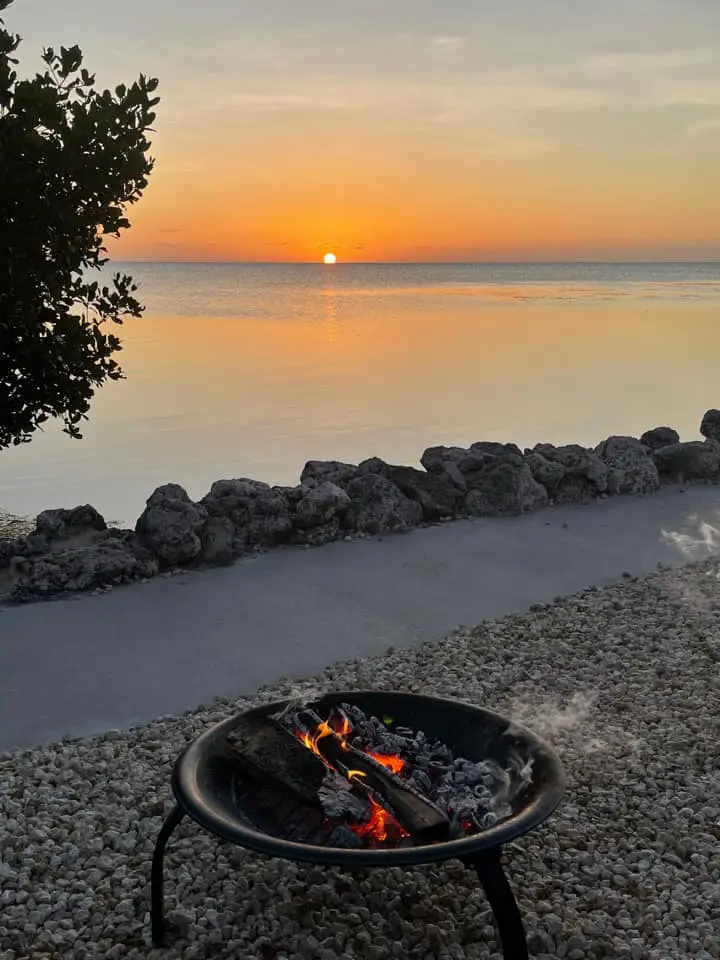 RV Campsite in Florida right on the beach at Encore Fiesta. Pictured is a fire pit, sidewalk, and the ocean with sun beyond
